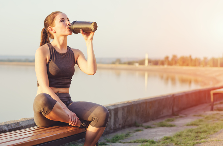 Fit woman drinking water on seawall